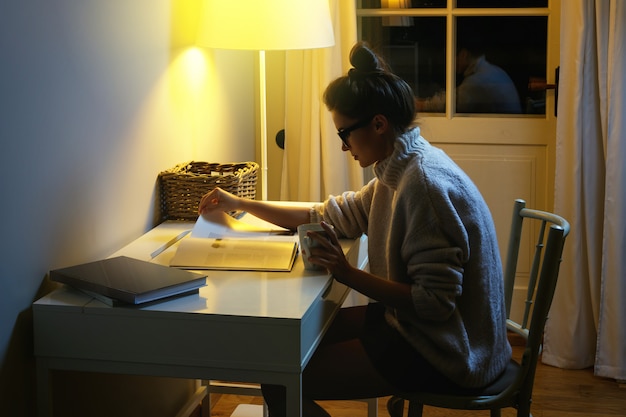 A person reviewing a printed CPF document on a desk, under a lamp light at night.
