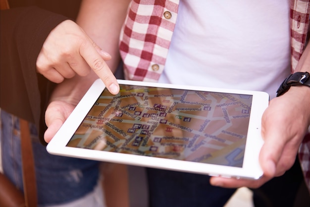 Wide shot of a map on a tablet, zoomed in on a neighborhood where the locations of the local social assistance centers are marked, each marked with an icon of a family and a heart, to indicate support and community, showing people using different devices to find social services available for them. The background is illuminated with sunlight, simulating an inviting and reassuring environment.