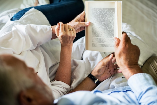 A volunteer reading a book to an elderly patient in a hospital. The patient is smiling, and the volunteer is engaged and compassionate. The scene is warm and comforting, highlighting the emotional support volunteers can provide.