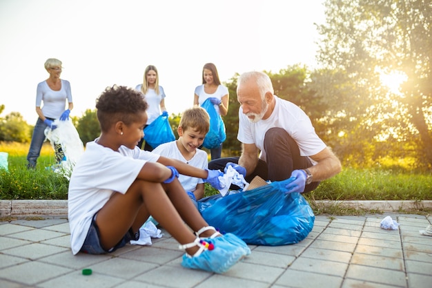 Volunteers in a neighborhood, wearing safety vests, picking up litter and putting it into trash bags. Include a mix of adults and children participating.
