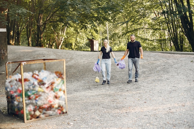 A group of volunteers sorting recyclables into different labeled bins after a community cleanup event. The setting is outdoors with natural light.