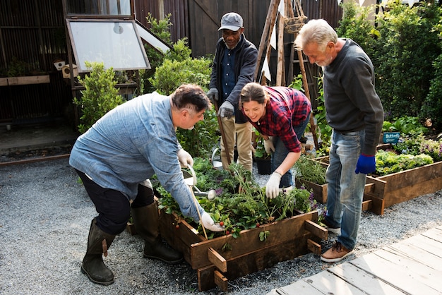 A group of volunteers, diverse in age and background, constructing raised garden beds from recycled pallets in a community garden, with tools and materials scattered around them.