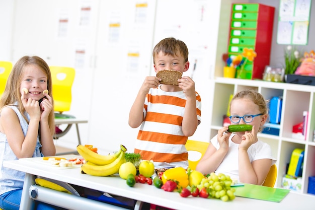 A group of children learning about healthy eating habits in a classroom setting, with fruits and vegetables on display, colorful and educational environment.