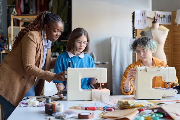 A group of women participating in a workshop, with one woman teaching the others how to use a sewing machine, representing skill development and community learning.