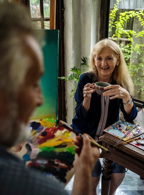 Seniors laughing and talking while participating in an art therapy workshop in a community center.