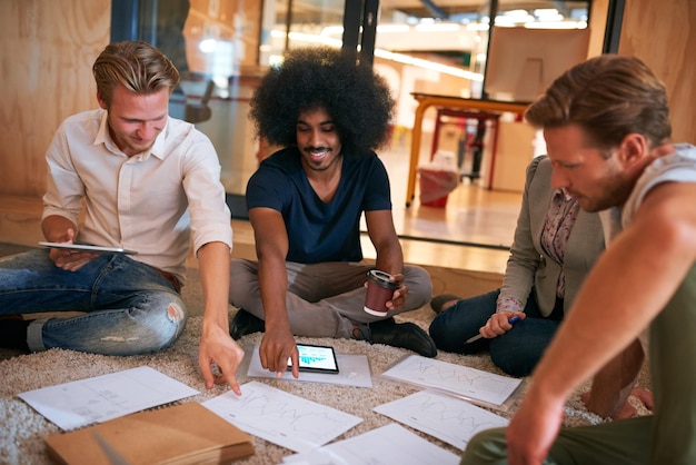 A group of diverse individuals are gathered around a table, reviewing blueprints and discussing plans for a community garden. They are pointing at different sections of the design, exchanging ideas and collaborating on the project. The atmosphere is positive and engaged.