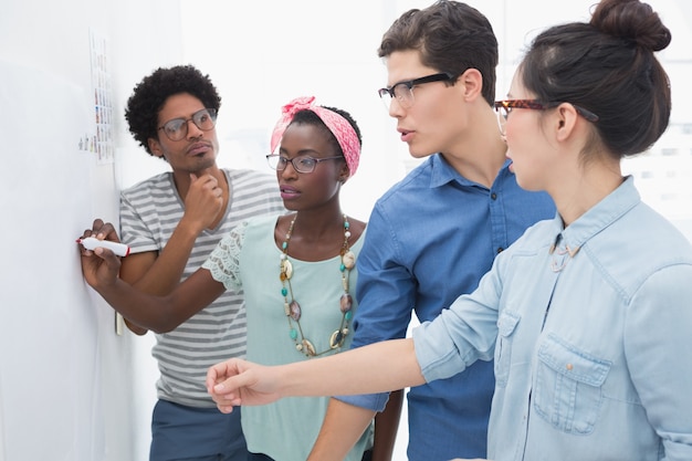 A diverse group of people participating in a workshop, with a whiteboard in the background displaying diagrams and bullet points under the title 