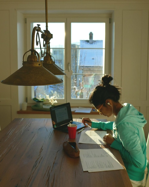A medium shot of a Brazilian family happily reviewing financial documents at their kitchen table, with sunlight streaming through the window, symbolizing hope and a fresh start after debt relief.