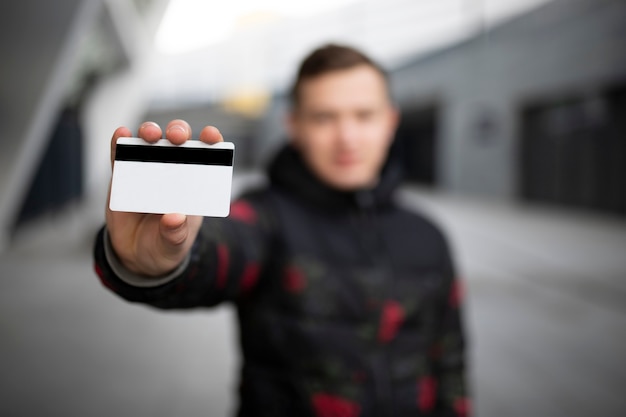 A person holding up their ID card, with a holographic security feature visible. The background is blurred, focusing on the security details of the ID.