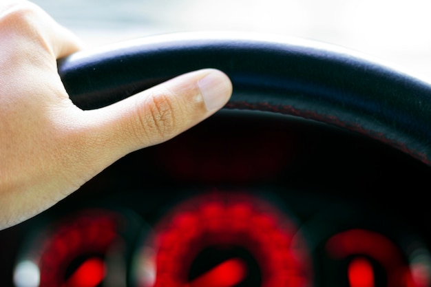 Close-up of a driver's hands on the steering wheel, with a concerned expression on their face. The dashboard is partially visible, showing a warning light illuminated. The image should convey a sense of awareness and responsibility while driving.