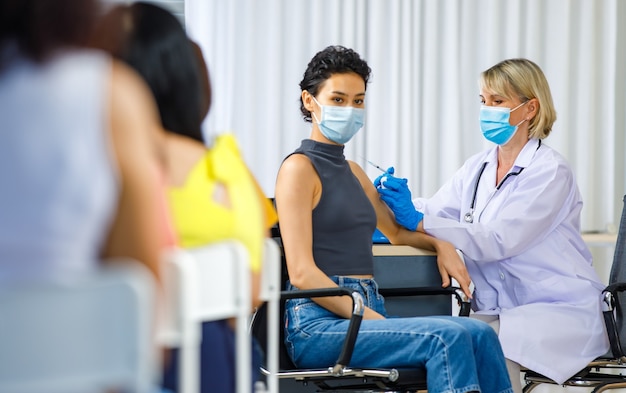 A diverse group of healthcare workers administering vaccines to patients of various ages, showcasing the process and accessibility of vaccination programs within a community health setting.