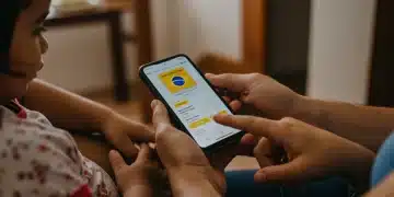 Mãos de uma família brasileira consultando informações do Auxílio Brasil em um smartphone, com foco na tela do aplicativo.