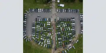 Aerial view of a crowded event parking lot with cars poorly parked on grass and asphalt, emphasizing logistical challenges before a community event.